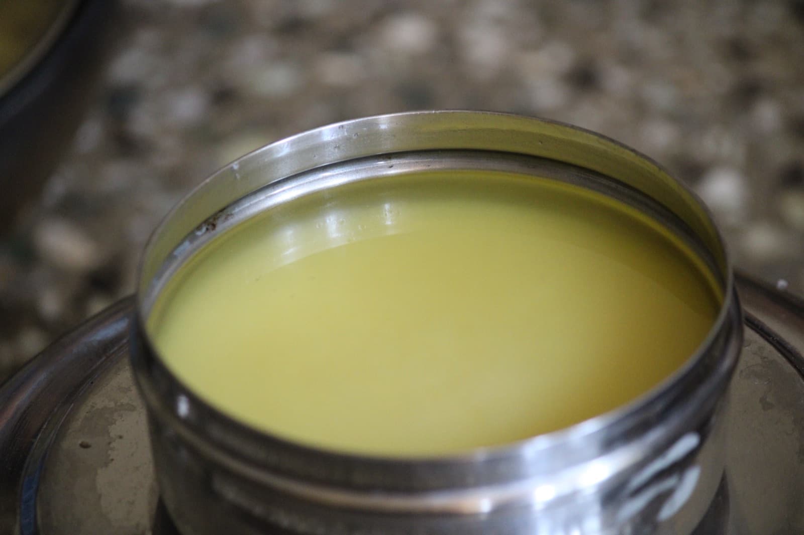 Freshly made ghee, clear and golden, in a round steel container