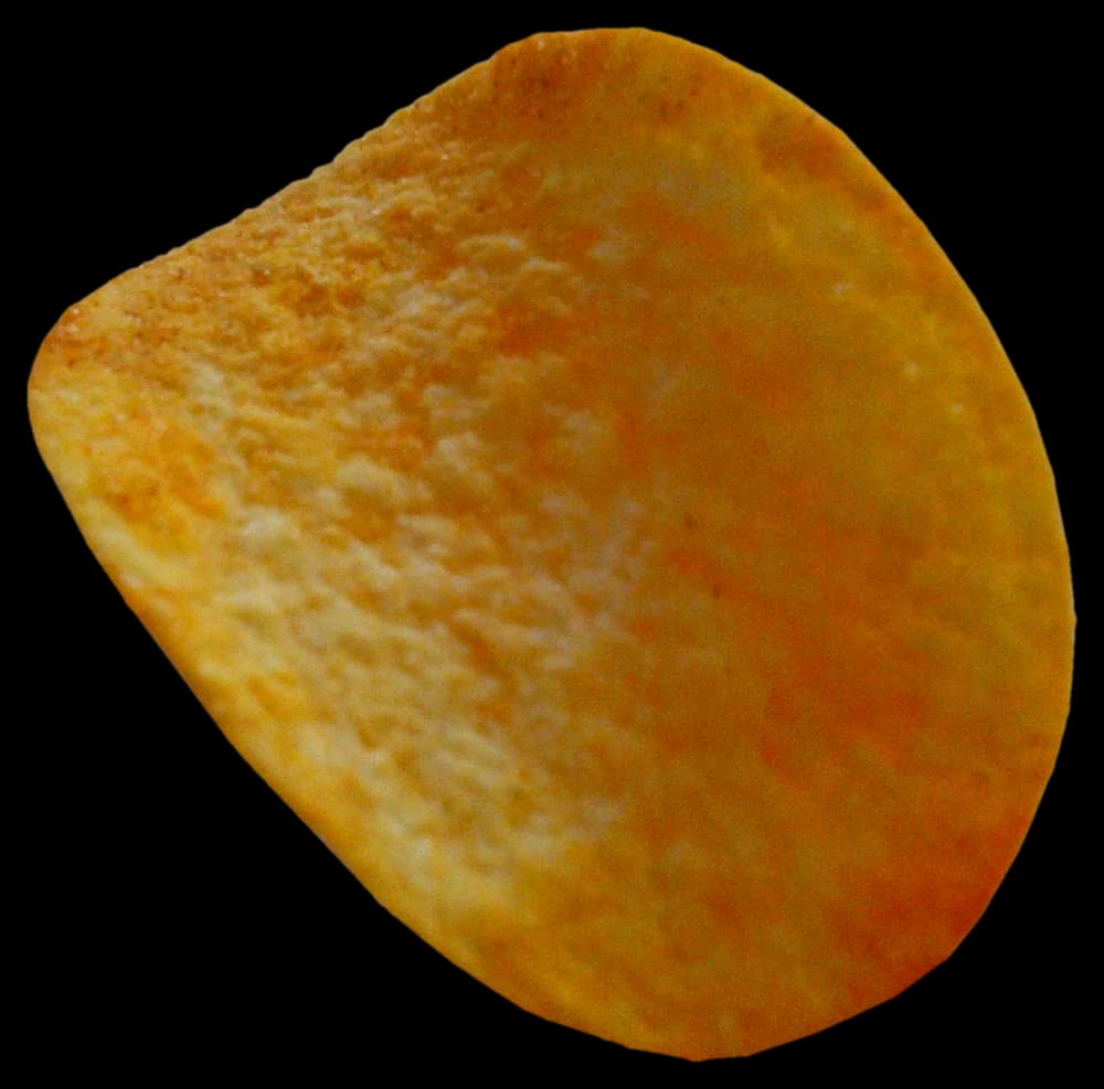 A single golden potato crisp floating in amber light